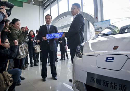 Qian Jun (L), the owner of a battery electric vehicle, is given the first free car plate for electric cars in Shanghai on Jan 23, 2012. [Photo/Xinhua] 