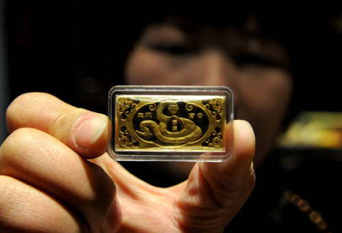 A saleswoman displays a gold bar for the Year of the Snake in Yiwu, Zhejiang province. Luxury goods makers incorporate snake motifs into their products to win more Chinese buyers. Zhang Jiancheng / For China Daily