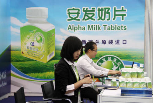 Workers arrange milk products imported from New Zealand at a dairy expo in Beijing. [Photo by Wu Changqing / for China Daily]