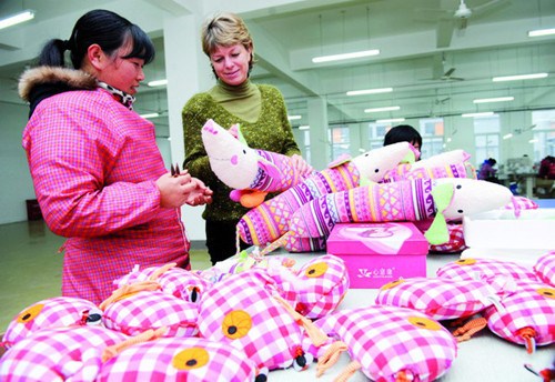 An overseas businesswoman examining cloth toys at Huainan Youtong Toy Co in East China's Anhui province. The Anhui toy maker exports its products to the European market. The per capita monthly income of its staff, most of whom are from the countryside, is nearly 2,000 yuan ($321). [Photo / China Daily]