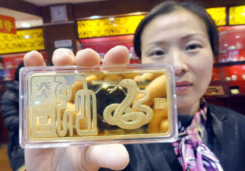 A staff member demonstrates a gold bar at a jewellery shop in Suzhou, east China's Jiangsu Province, Dec. 18, 2012. In 2012, consumers in China bought a total of 832.18 tons of gold, 71.13 tons, or 9.35 percent, more than the figure of 2011, according to the latest statistics released by the China Gold Association on Saturday. (Xinhua)