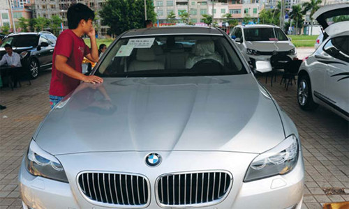 Potential buyer checks a BMW in Qionghai, Hainan province. Premium German carmakers BMW and Audi continue to outpace Mercedes-Benz in network expansion across China, especially in smaller cities. [Meng Zhongde/For China Daily]