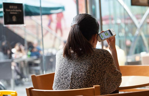 A woman using her smartphone's WeChat service to talk to her friend. Tencent's WeChat is experiencing strong challenges from its counterparts, including Phone Plus, which is also an online chatting app developed by China-based Longmaster Information & Technology Co. [Photo/China Daily]