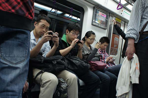 Four people playing online games on their way to office by subway in Beijing. Playing game apps with mobile devices is now a popular way for many white-collar workers to pass time during commutes. Games command 32 percent of customers' total time in using mobile devices, says a recent study conducted by market research firm Flurry Analytics. Provided to China Daily