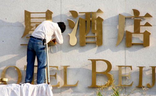 A worker fixing a hotel logo on the outside wall of a hotel inn in Beijing managed by an overseas company. China has more than 60,000 hotels with 14,000 given stars. The rapid development of hotels in the country is in sharp contrast to the slowdown of the global hotel industry. [Photo/Provided to China Daily]
