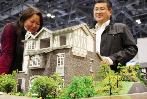 Potential buyers examine a model of a villa project at a housing show in Beijing. In May, 82 luxury apartments priced at more than 15 million yuan ($2.45 million) changed hands in the capital, up 74 percent month-on-month. [Photo/China Daily]