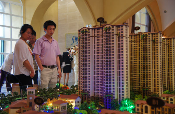 Property buyers examine the real estate models in Baoding, Hebei province. In the context of a wide-ranging credit crunch, home buyers may expect price cuts at some projects if developers find themselves caught in a lack of capital. [Photo/Provided to China Daily]