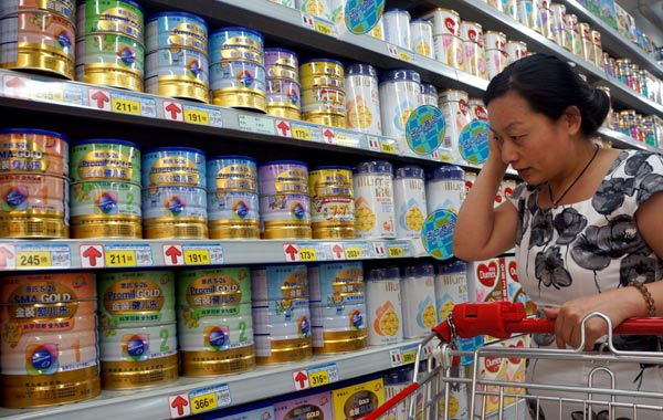 A woman looks at imported milk powder at a supermarket in Zhengzhou, Henan province. [Photo/Provided to China Daily]