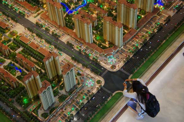 A potential homebuyer takes a photo of a property display model in Beijing. Home prices have continued to increase in most major cities across the country despite the central governments efforts to curb rising housing prices. FAN JIASHAN/FOR CHINA DAILY