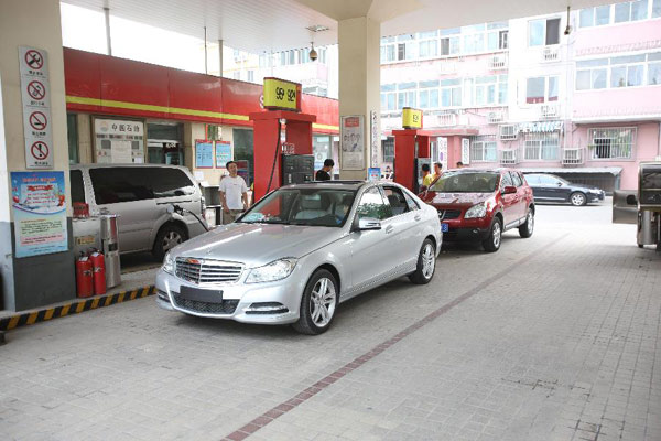 Workers fuel vehicles at a gas station in Beijing, capital of China, July 19, 2013. According to National Development and Reform Commission, the retail price of gasoline and diesel oil in China will be raised by 325 Yuan (52.9 U.S.dollars) and 310 Yuan (50.5 U.S.dollars) per tonne respectively starting from July 20. (Xinhua/Zhao Dingzhe)