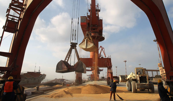 Workers are loading imported soybean at Nantong port, Jiangsu province. Despite plentiful harvests, China is still challenged by over-demand for grains, with imports set to continue to grow in the second half of the year. Xu Congjun/for China Daily