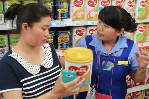 Mu Liping (left) checks with a saleswoman at a supermarket in Beijing on Sunday whether her newly bought Dumex baby formula should be recalled. Dumex announced it was recalling 12 batches of products in China that may be contaminated. Mu found her purchase didn't belong to the recalled batches and left with the baby power. [Cui Meng/China Daily]