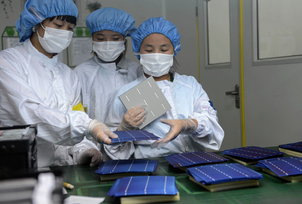 A quality inspector from a solar company in Hangzhou in Zhejiang province checks solar cell units. The Europe Commission endorsed a negotiated settlement with China that sets a minimum price and a volume limit on EU imports of Chinese solar panels through the end of 2015. [Photo/China Daily] 