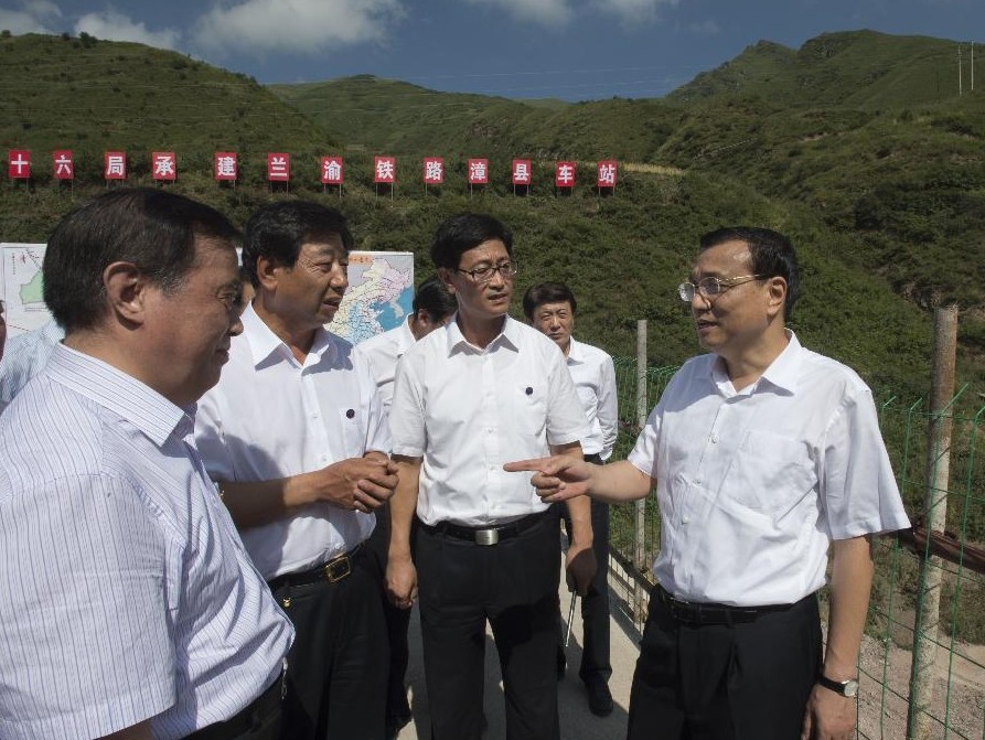 Chinese Premier Li Keqiang (R) talks with officials of the China Railway Corporation at the construction site of the Zhangxian Railway Station in Zhangxian County, Dingxi City, northwest China's Gansu Province, Aug. 18, 2013. The Zhangxian Railway Station is a stop of the Lanzhou-Chongqing railway line which links Lanzhou city in Gansu with southwest China's Chongqing municipality. Premier Li made an inspection tour to Dingxi and Lanzhou of Gansu from Aug. 17 to 19. (Xinhua/Li Xueren)