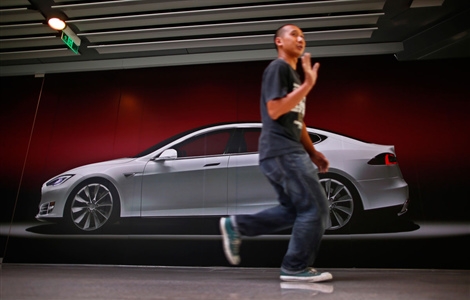 A man gestures as he walks past a billboard-sized photo of the Tesla Model S car, outside the boarded-up first China flagship showroom of Tesla at an office-shopping complex in Beijing.