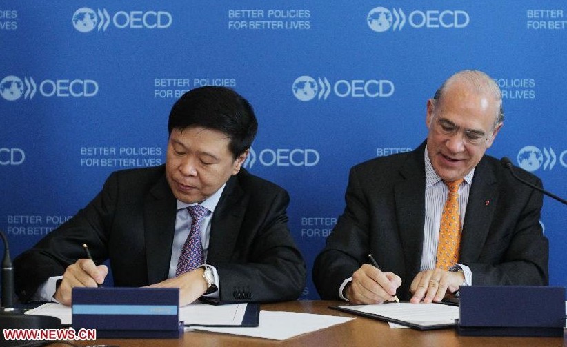 Wang Jun (L), Administrator of the State Administration of Taxation of China, and Angel Gurria, Secretary-General of the Organization for Economic Co-operation and Development (OECD), attend the signing ceremony at the headquarters of OECD in Paris,France, Aug. 27, 2013.(Xinhua/Gao Jing) 