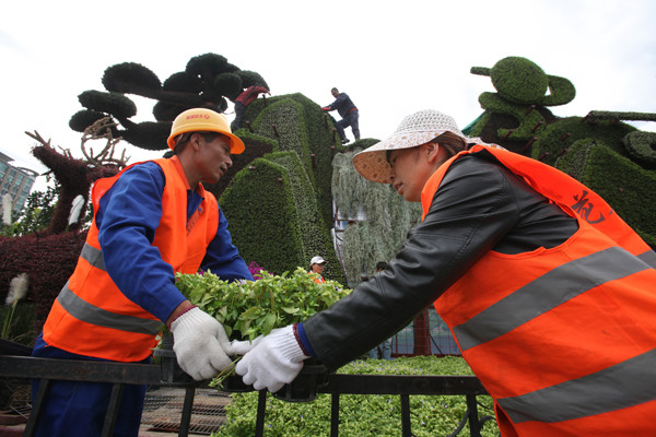 Workers put the final touches to a floral arrangement featuring a landscape. [Photo by Wang Jing/China Daily]