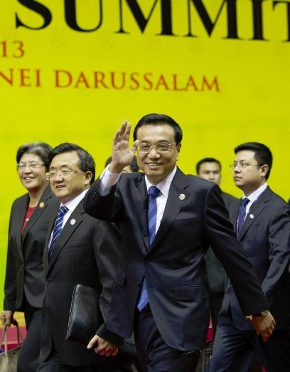 Chinese Premier Li Keqiang (front) waves to journalists before taking a group photo with other leaders who attend the 8th East Asia Summit (EAS) in Bandar Seri Begawan, Brunei, Oct. 10, 2013. (Xinhua/Huang Jingwen)