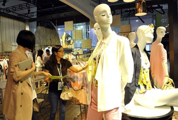 A buyer examines garments at the China Import and Export Fair in Guangzhou, Guangdong province. The fair, also known as Canton Fair, opens on Tuesday for its autumn session. Liang Xu/Xinhua