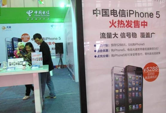Customers inspect Apple Inc's iPhone 5 at a China Telecom store in Haikou, Hainan province.[Photo / Provided to China Daily]