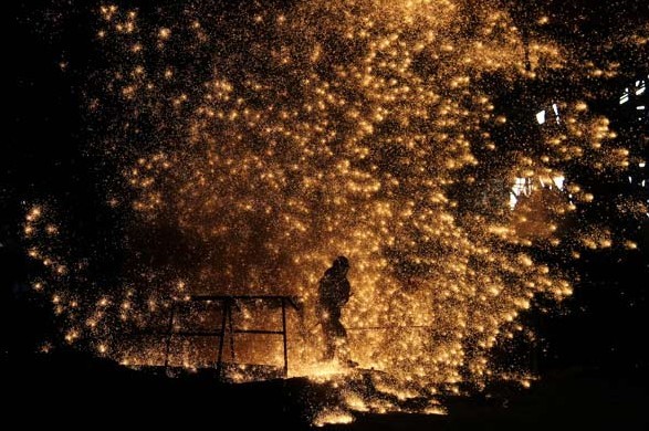 Workers labor at an iron and steel company in Laiwu, Shandong province. The industry is burdened with excess capacity, and its losing money. The central government has announced measures to cut the sectors capacity and improve its efficiency. Xu Hongxing / For China Daily  