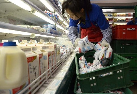 An employee stocks dairy products at a supermarket in Beijing.[Photo/China Daily] 