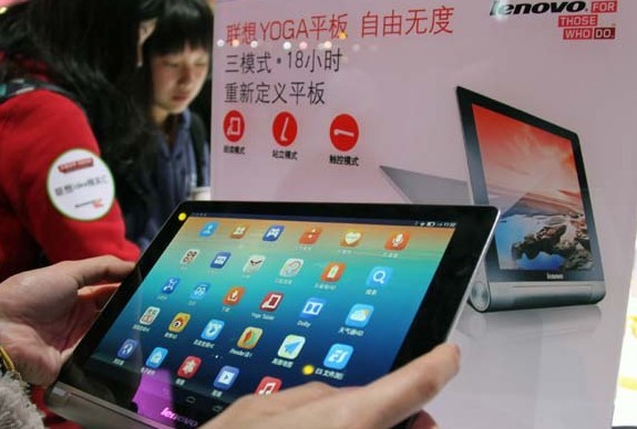 A visitor photographs Lenovo Group Ltd's Yoga Tablet at a show in Beijing. The company's second-quarter revenue was $9.8 billion, a 13 percent year-on-year gain.[Photo/China Daily]   