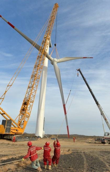 Turbine blades are hoisted onto a windmill at a wind farm in Hami, in the Xinjiang Uygur autonomous region. Xinjiang is one of the biggest wind-power generating regions in China. The country is trying to increase the proportion of renewable energy in its total energy consumption mixture. Zhang Jiangang / For China Daily