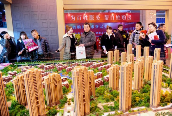 Potential homebuyers look at models of residential property on Friday at a real estate trade show in Shenyang, Liaoning province. Provided to China Daily