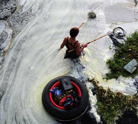 A man fishes in the Bahe River in Xi'an, Shaanxi province, in May. The waterway's heavy pollution is seen in the white foam on its surface. Ding Haitao / Xinhua  