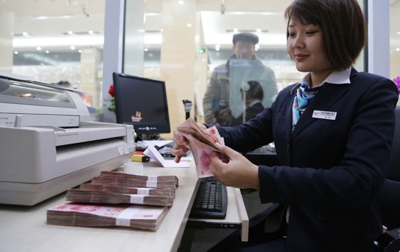 An employee counts yuan bills at a bank in Xuchang, Henan province. The value of the yuan retreated on Thursday, along with other emerging market currencies. Provided to China Daily  