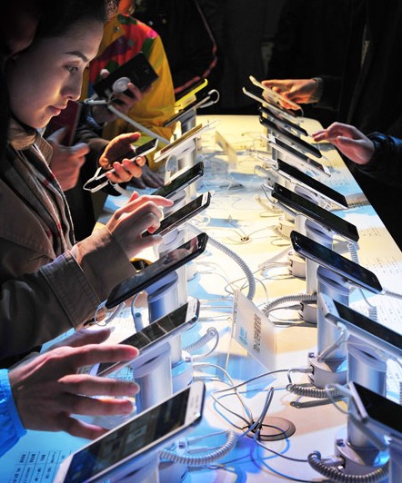 People try out mobile handsets at a store in Guangzhou, Guangdong province. The government issued licenses for virtual network services to 11 privately owned operators on Thursday. LU HANXIN / XIN\HUA  