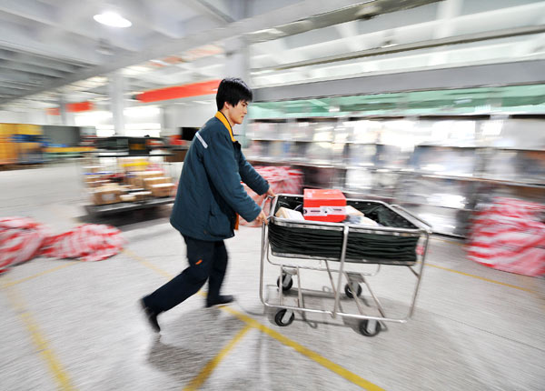 A worker pushes express parcels to delivery vehicles at the China Postal Express and Logistics Co Ltd branch in Yinchuan, the Ningxia Hui autonomous region. The State-owned company has been losing market share to private couriers amid fierce competition. PENG ZHAOZHI / XINHUA