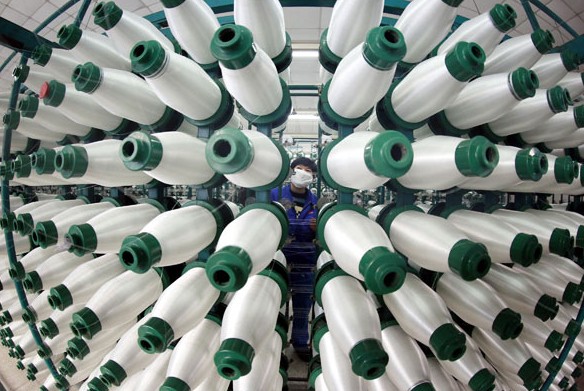A worker checks spindles at Jiujiang Xinxing Fiberglass Co Ltd in Jiujiang, Jiangxi province, on Wednesday. The index of new export orders for manufactured products fell to 49.8 in December from 50.6 in November. LIU HAIYAN / FOR CHINA DAILY  