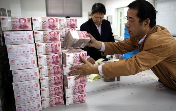 Employees count money at a bank in Wuxi, Jiangsu province. The yuan's strength will grow in 2014, analysts said, as the US is in no hurry to tighten credit by driving up interest rates. Chen Wei /for China Daily