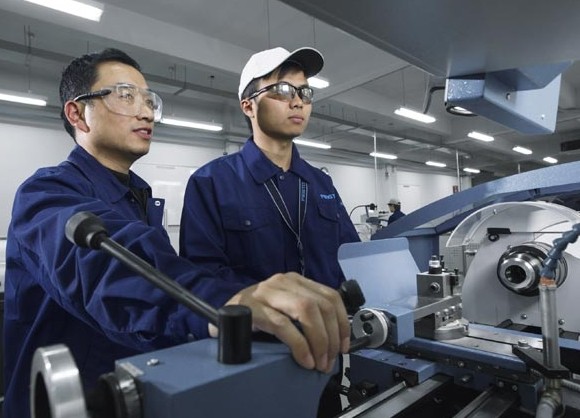 A senior worker (left) conducts one-on-one training session for an intern at Festo (China) Ltd's newly upgraded regional service center in Jinan, Shandong province. Provided to China Daily