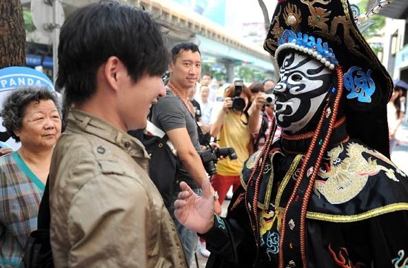A face-changing artist in Taipei performs for tourists at a Chengdu Municipal Tourism Administration event to promote the city's folk customs in July. In face-changing performances, artists repeatedly quickly change the masks they are wearing. Tao Ming / China Daily  