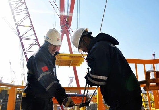 Workers at a CNOOC subsidiary install equipment in Qingdao, Shandong province. CNOOC's net 2013 output is estimated at 412 million barrels of oil equivalent, including 61 million BOE from Nexen Inc. Jiang Zuofeng / For China Daily  