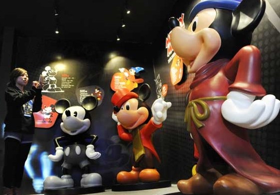 Visitors take photos of Mickey and Minnie Mouse at the exhibition commemorating the Walt Disney Company's 90th anniversary in Zhengda Square in Shanghai on Dec 18, 2013. Provided to China Daily