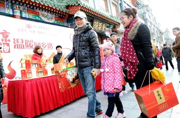 A family in Beijing buys a Quanjude Peking roast duck hamper at Qianmen Pedestrian Street ahead of the Spring Festival holiday. [Photo by Jiang Dong/chinadaily.com.cn]  
