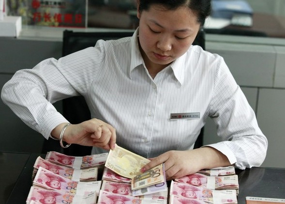 An Industrial and Commercial Bank of China Ltd employee counts euros and yuan in Huaibei, Anhui province. China's surplus in its current account reached $49.8 billion in the fourth quarter of 2013. Xie Zhengyi / For China Daily  