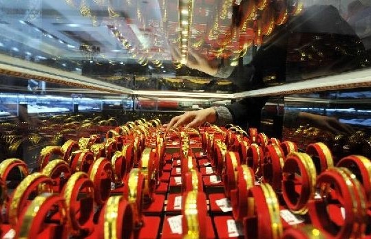 A salesperson arranges gold jewelry at a gold store in Lin'an City, east China's Zhejiang Province, Feb. 10, 2014.(Xinhua/Hu Jianhuan) 
