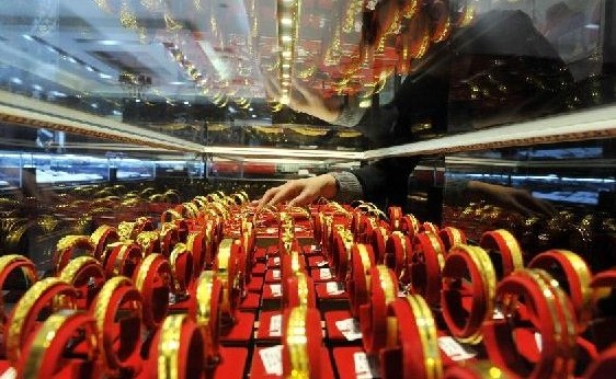 A salesperson arranges gold jewelry at a gold store in Lin'an City, east China's Zhejiang Province, Feb. 10, 2014. 