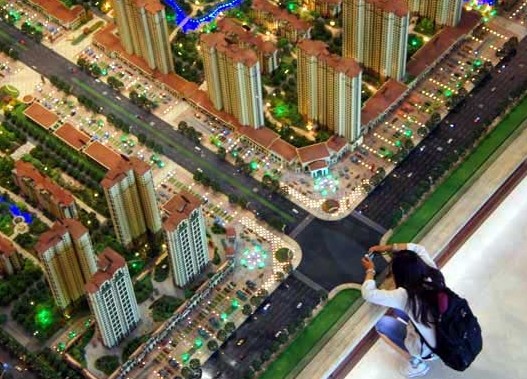     A potential homebuyer takes a photo of a property display model in Beijing. [File photo / China Daily]   