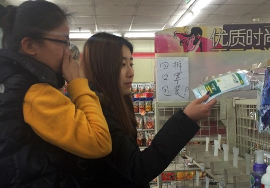 Customers choose masks from a nearly empty shelf at a store in Beijing on Wednesday. Masks and air purifiers have been flying off the shelves in the capital because of heavy air pollution that began to shroud the city from early last week. Liu Zhe / China Daily   