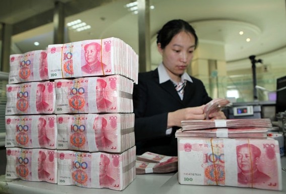 A clerk counts currency at a bank in Ganyu county, Jiangsu province, earlier this month. Si Wei / for China Daily 