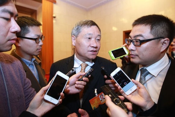 Xiao Gang (center),chairman of the China Securities Regulatory Commission,speaks with reporters after a meeting at the ongoing annual session of the National People's Congress. Provided to China Daily   
