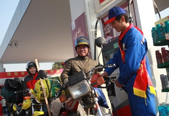 A worker of Sinopec Guangdong Oil Products Company offers free gas to migrant workers who are traveling home for Spring Festivals by motorbike in Foshan, Guangdong province, on Jan 23, 2014. Foshan mayor said the city plans to distribute 20% of public rental houses to migrant workers. [Photo / China Daily]  