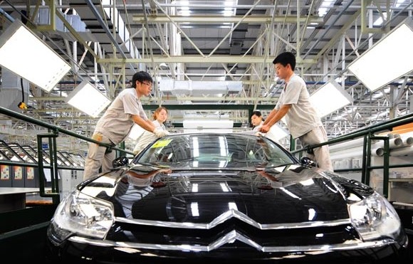 Workers fix protective film onto a car at Dongfeng Peugeot Citroen Automobile Co Ltd in Wuhan, Hubei province. Foreign direct investment in Central China surged 75 percent to $2.62 billion in the Jan-Feb period, the Ministry of Commerce said. Cheng Min / Xinhua  