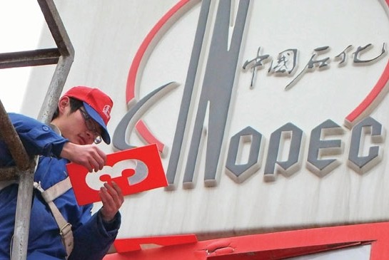 Workers update a sign displaying gasoline and diesel prices at a Sinopec gas station in Yichang, Hubei province. [Photo/China Daily] 